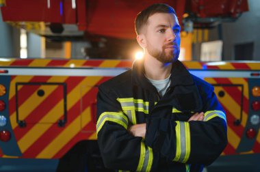 İtfaiyeciler itfaiye aracının yanındaki koruyucu kıyafetli adam. Koruma, tehlikeden kurtarma. İtfaiye.