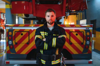 İtfaiyeciler itfaiye aracının yanındaki koruyucu kıyafetli adam. Koruma, tehlikeden kurtarma. İtfaiye.