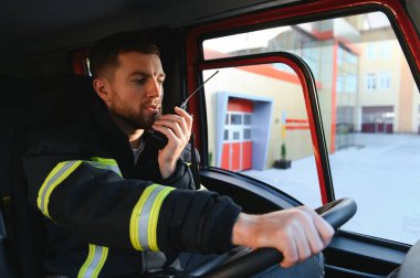 İtfaiyeci itfaiye aracı kullanırken telsiz kullanıyor..