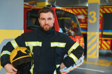 İtfaiyeciler itfaiye aracının yanındaki koruyucu kıyafetli adam. Koruma, tehlikeden kurtarma. İtfaiye.