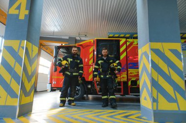 İtfaiye istasyonunda duran üniformalı iki genç itfaiyecinin portresi..