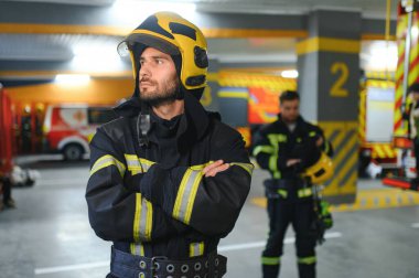 İtfaiye istasyonunda duran üniformalı iki genç itfaiyecinin portresi..