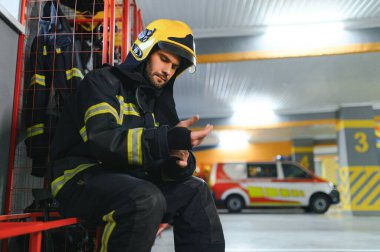 İtfaiyeci itfaiyede bankta oturuyor..