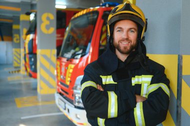 İtfaiyeciler itfaiye aracının yanındaki koruyucu kıyafetli adam. Koruma, tehlikeden kurtarma. İtfaiye.