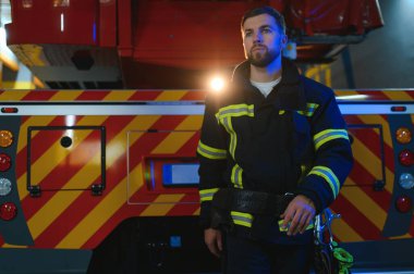 Görevdeyken itfaiyeci portresi. İtfaiyeci kasklı, itfaiye arabasının yanında..