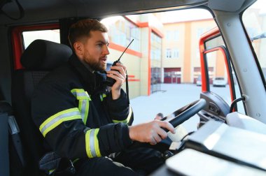 İtfaiyeci itfaiye aracı kullanırken telsiz kullanıyor..