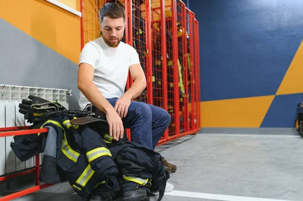 Fireman changing clothes and fastening his helmet in fire department.