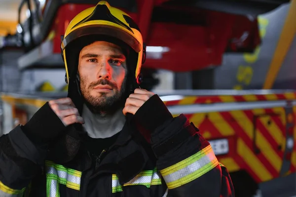 Firefighter portrait on duty. fireman with helmet near fire engine.