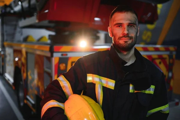Firefighter portrait on duty. fireman with helmet near fire engine.