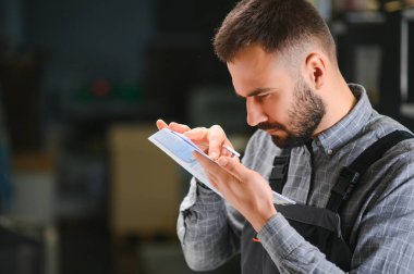 Yazıcı çalışanı yazdırma sürecinin kalitesini kontrol ediyor ve büyüteçle renkleri kontrol ediyor.