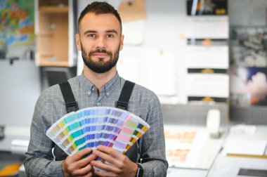 Baskı imalatında renk örnekleriyle ayakta duran daktilocu.
