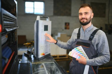 Modern matbaada baskı kalitesini kontrol eden grafiksel mühendis veya işçi.