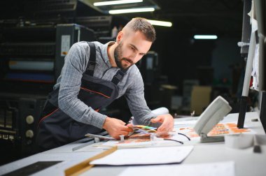 Modern matbaada baskı kalitesini kontrol eden grafiksel mühendis veya işçi.