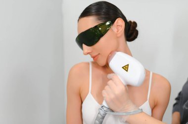 Lazer epilasyon kadının yüzünde veren güzellik uzmanı Close-Up.