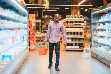 Afrikalı adam süpermarketten alışveriş yapıyor. Elinde alışveriş sepeti tutan yakışıklı adam..