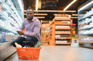 Genç Afrikalı adam süpermarketin market bölümünden alışveriş yapıyor..