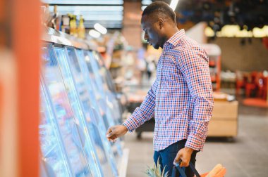 Genç Afrikalı adam süpermarketin market bölümünden alışveriş yapıyor..