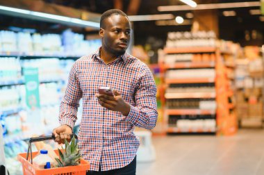 Genç Afrikalı adam süpermarketin market bölümünden alışveriş yapıyor..