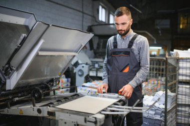 Modern matbaada baskı kalitesini kontrol eden grafiksel mühendis veya işçi.