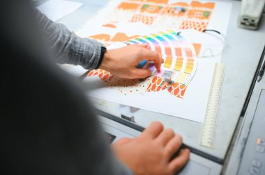 Çalışma üniformasında modern ofset baskı makinesi ve operatör ile ev içi yazdırma Kalite ve baskı süreci kontrol.