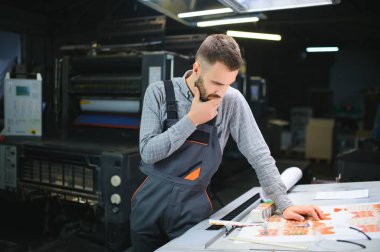 Modern matbaada baskı kalitesini kontrol eden grafiksel mühendis veya işçi.