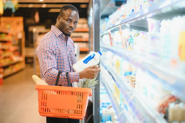 Young african man buying in grocery section at supermarket.