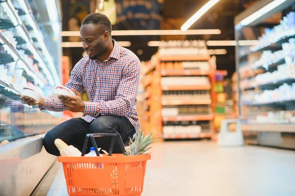 Young african man buying in grocery section at supermarket.