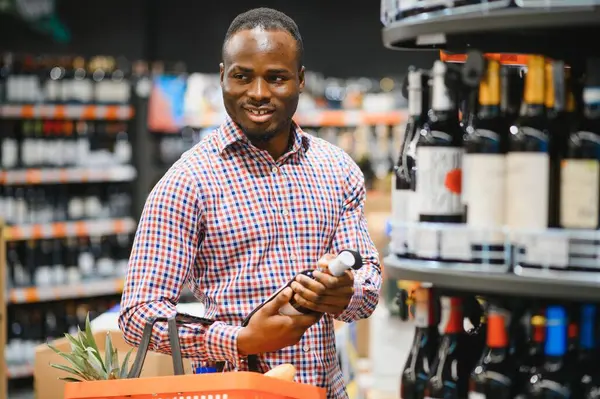 African American man in grocery store buying wine.