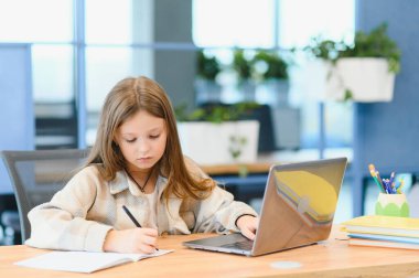 Okuldaki ilk günüm. Sevimli ve mutlu küçük kız çocukları dizüstü bilgisayar kullanıyor, online e-öğrenim sistemi üzerinden çalışıyorlar..