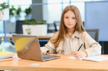 Okuldaki ilk günüm. Sevimli ve mutlu küçük kız çocukları dizüstü bilgisayar kullanıyor, online e-öğrenim sistemi üzerinden çalışıyorlar..