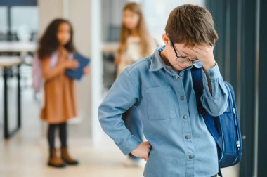 Okuldaki üzgün çocuk elleriyle yüzünü örtüyor. Okulda zorbalık..