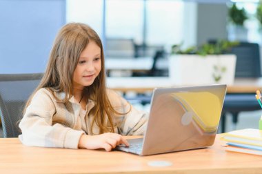 Okuldaki ilk günüm. Sevimli ve mutlu küçük kız çocukları dizüstü bilgisayar kullanıyor, online e-öğrenim sistemi üzerinden çalışıyorlar..