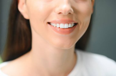 Stomatoloji konsepti, güçlü beyaz dişli bir kızın kısmi portresi. Dişçide, stüdyoda, kapalı mekanda genç bir kadının yakın çekimi..