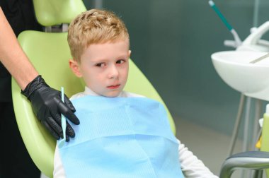 Scared red-haired boy crying at reception at dentist in dental chair. Pediatric dentistry.