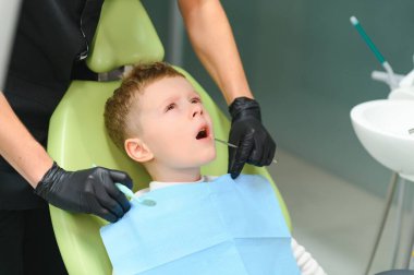 Scared red-haired boy crying at reception at dentist in dental chair. Pediatric dentistry.