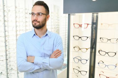 Sağlık, görme ve görme duyusu kavramı. Optik mağazasında gözlük seçen mutlu adam, seçici odaklı..