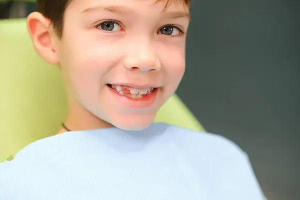 Little boy sits on dentist\'s chair in good mood after dental procedures. Young patient with healthy teeth.