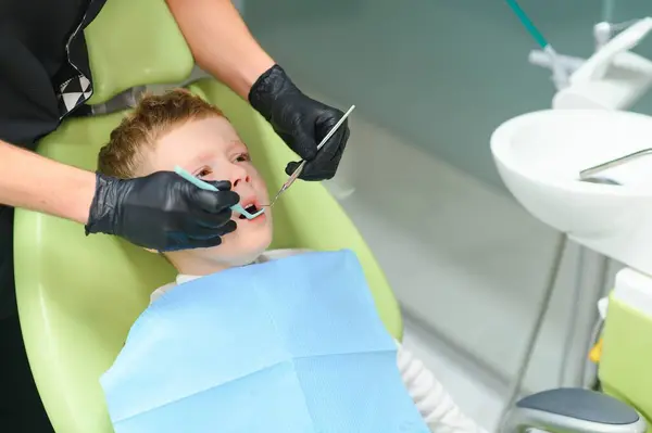 Scared red-haired boy crying at reception at dentist in dental chair. Pediatric dentistry.