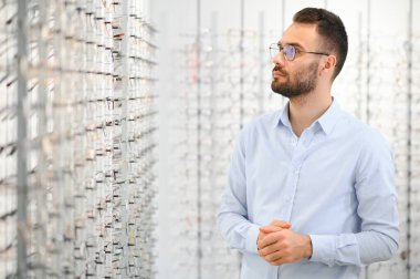 Sağlık, görme ve görme duyusu kavramı. Optik mağazasında gözlük seçen mutlu adam, seçici odaklı..