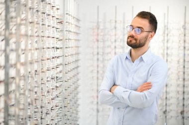 Genç adam optik dükkanında gözlük seçiyor..