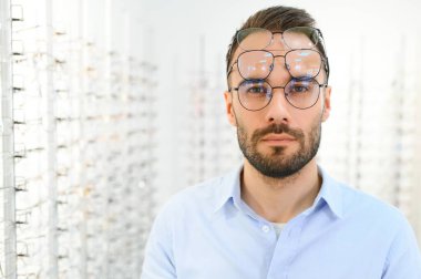 Adam optik dükkanından gözlük seçiyor..
