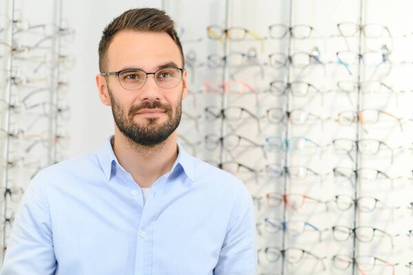 Man choosing glasses in eyewear store.