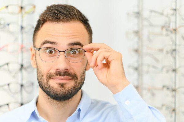 Man choosing glasses in eyewear store.