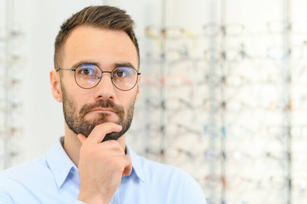 Man choosing glasses in eyewear store.