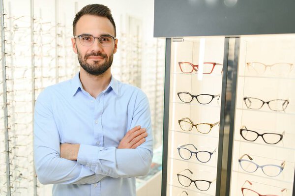 Young man choosing spectacles at optic shop.