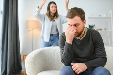 Aile kavgası, evdeki kanepede oturan kadın ve erkek. Kızgın kadın kocasına bağırıyor..