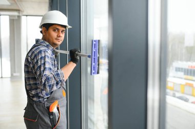 Erkek profesyonel temizlik işçisi, özel ekipmanlı bir mağazanın camlarını ve pencerelerini temizler..