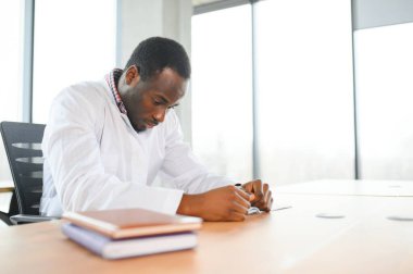 Afrikalı doktor hastanedeki masada yorgun oturuyor..