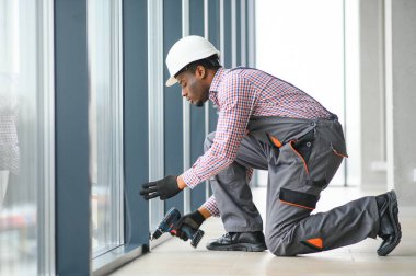 Evdeki oturma odasına plastik pencereler monte eden ya da ayarlayan işçi