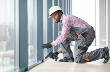 İnşaat işçisi plastik pencereyi tornavidayla tamir ediyor. Pankart tasarımı